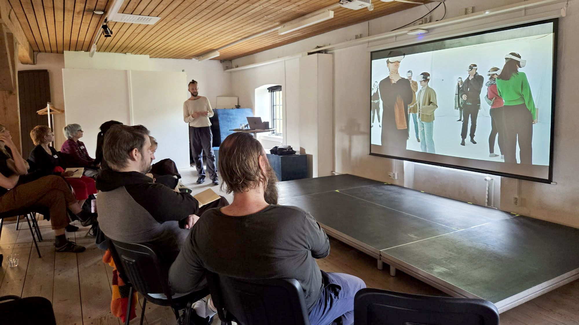 Artist Jakob Skote on stage giving a talk for an interested audience